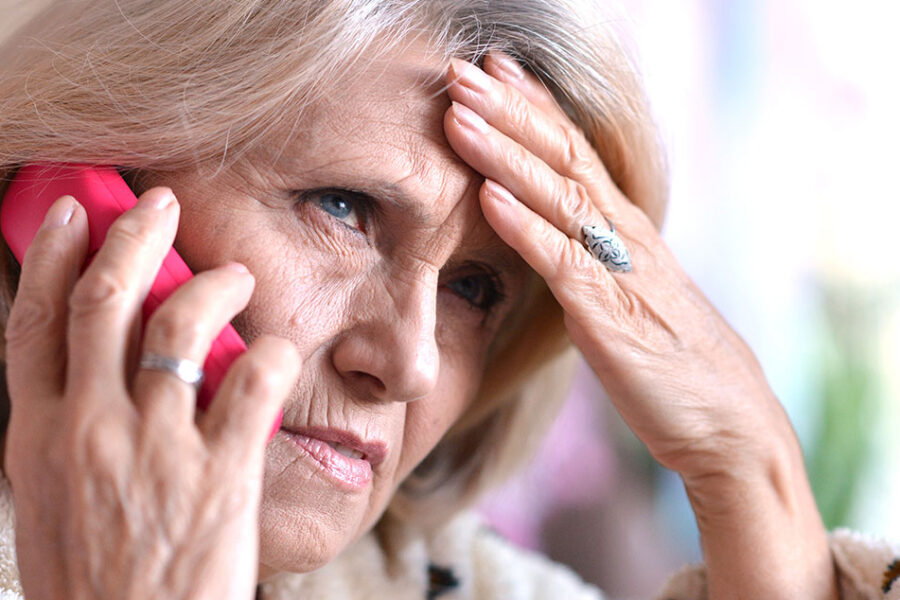 Photo of a worried older woman on phone trying to remember the tax scam tips she's read before.