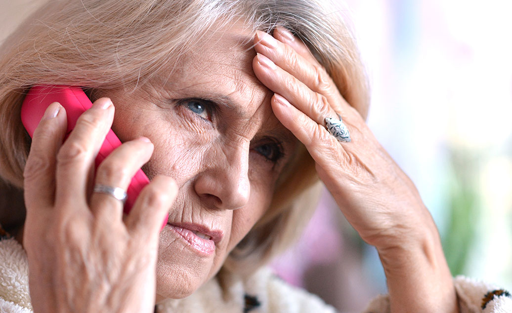 Photo of a worried older woman on phone trying to remember the tax scam tips she's read before.