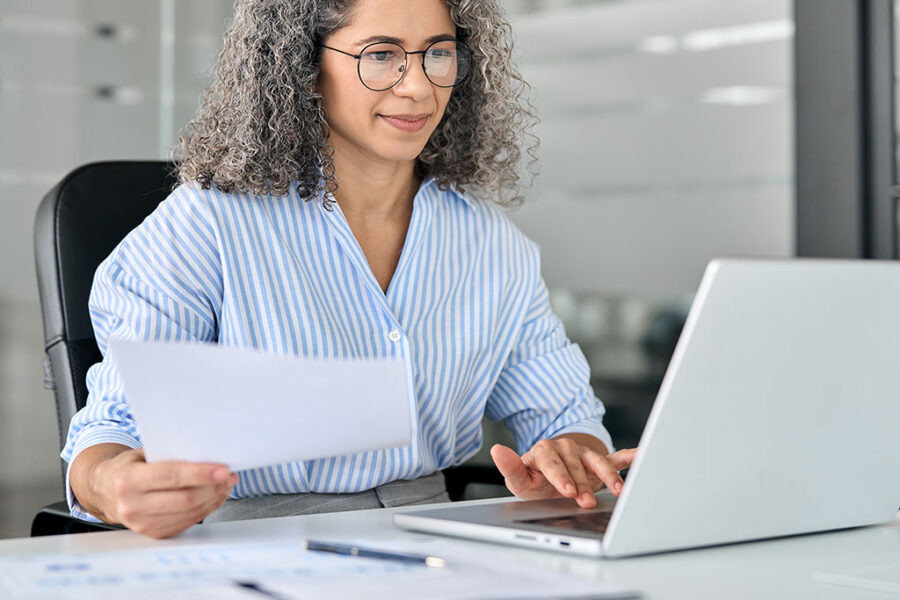 Mature Professional Woman At Desk Computer using postive pay system